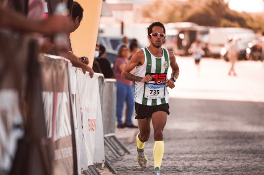 Athlete in sportswear running a marathon on a sunny day with spectators.