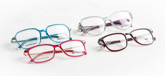 A collection of four colorful glasses on a white surface showcasing fashionable eyewear styles.