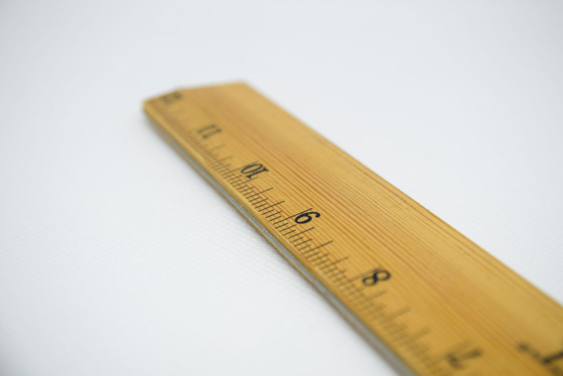 A wooden ruler with numbered markings on a plain white background.