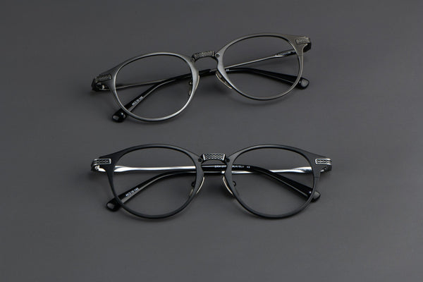 Close-up of two pairs of round black eyeglasses on a dark surface, highlighting modern eyewear style.