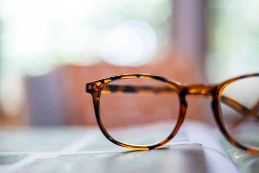 Detailed close-up of fashion-forward tortoiseshell eyeglasses on a blurred background.