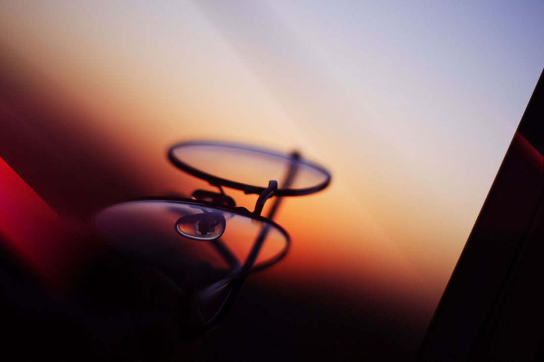Close-up of eyeglasses reflecting a vibrant sunset, showcasing an artistic and colorful backdrop.