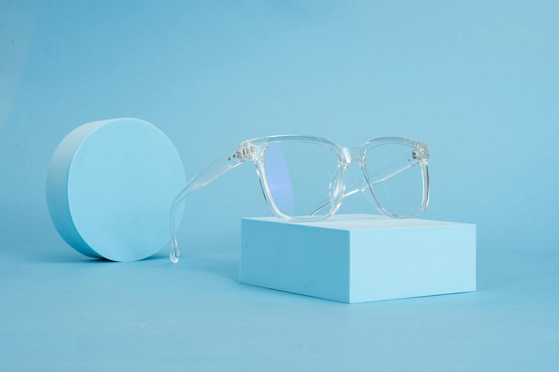 Clear eyeglasses on blue geometric shapes, emphasizing minimalist design and clean lines.