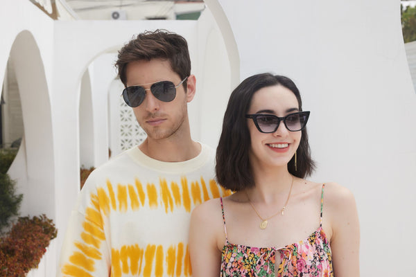 A fashionable couple wearing sunglasses, smiling under the bright sun. Perfect for lifestyle imagery.