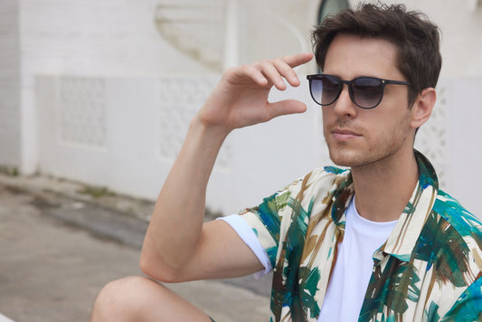 Trendy man wearing sunglasses and a colorful shirt, enjoying a sunny day outside.