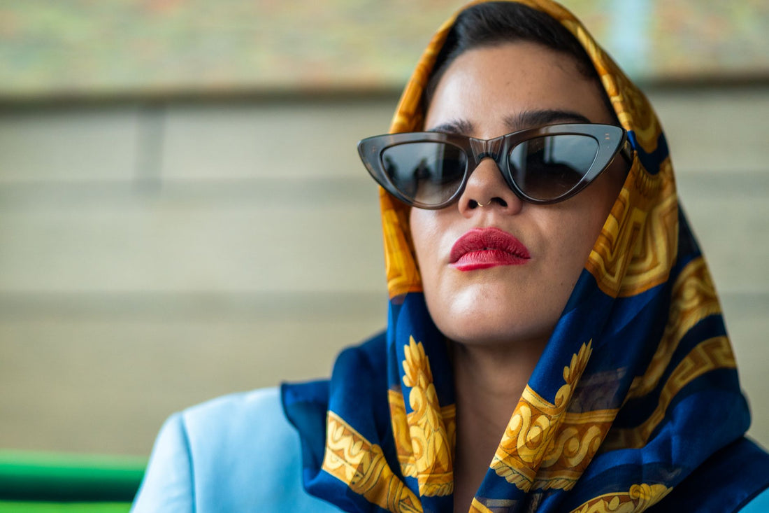 Portrait of a fashionable woman wearing sunglasses and a vibrant scarf outdoors.