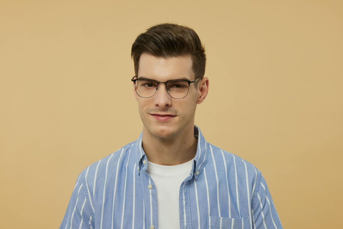 Portrait of a young man wearing stylish eyeglasses and a blue striped shirt.