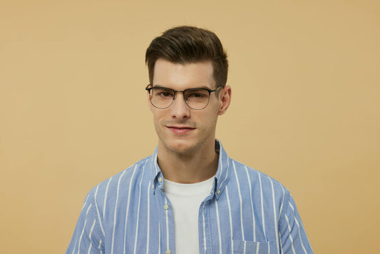 Portrait of a young man wearing stylish eyeglasses and a blue striped shirt.