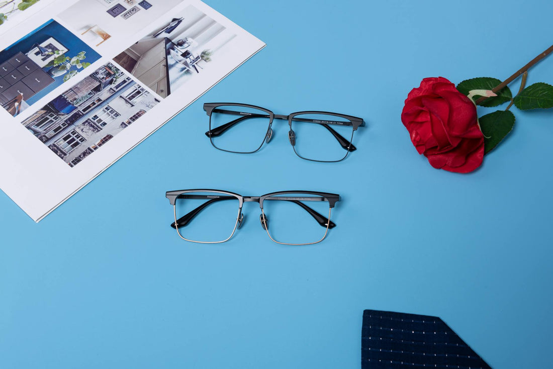 Stylish eyeglasses paired with a red rose and magazine on a blue backdrop.