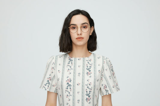 Portrait of a young woman in a floral dress and glasses, studio shot.