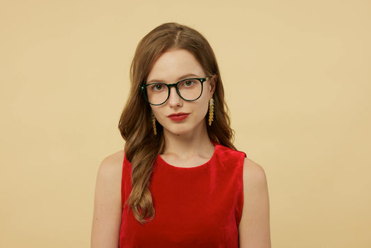 Sophisticated portrait of a young woman in red velvet, wearing chic eyeglasses and earrings.