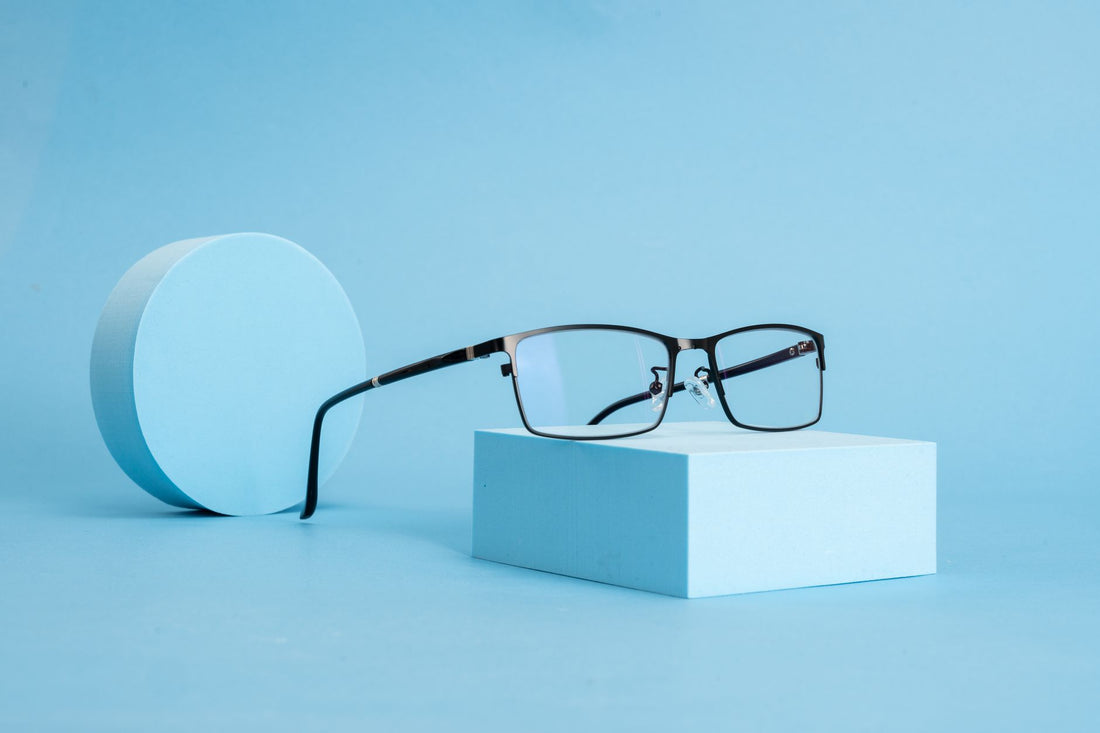Elegant eyeglasses displayed on a blue geometric background, showcasing modern style and minimalism.