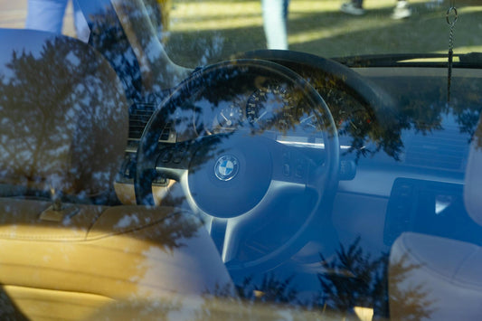 View through a car windshield reflecting trees, showcasing an artistic interplay of nature and technology.