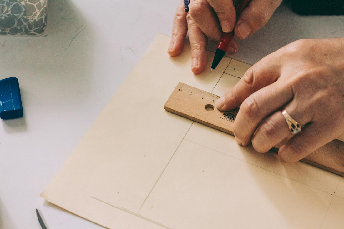 Close-up of hands using a ruler to draw lines on paper.
