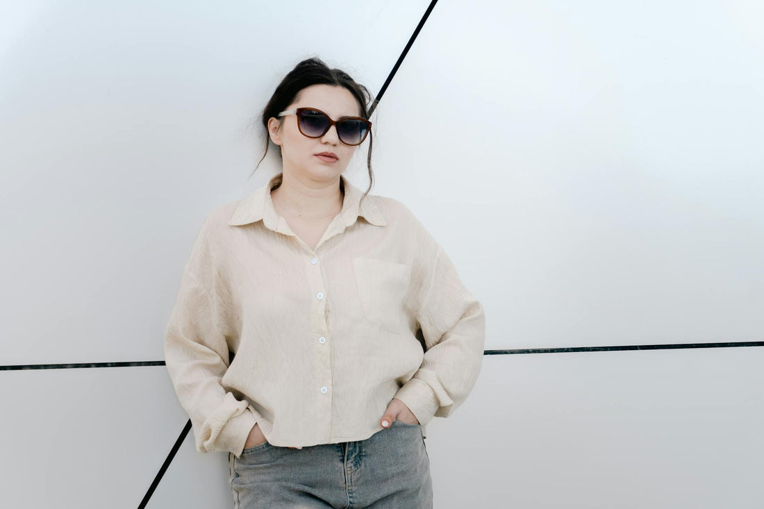 Trendy woman in sunglasses leaning against a geometric wall, showcasing fashion and confidence.