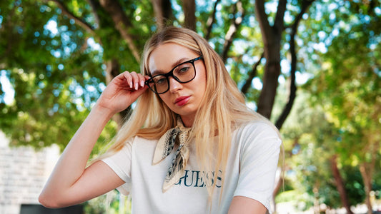 Fashionable woman in glasses poses outdoors, showcasing casual style.