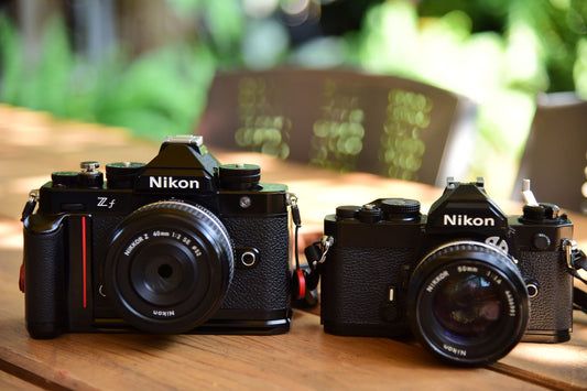 Two vintage Nikon cameras displayed outdoors, capturing photographic nostalgia.