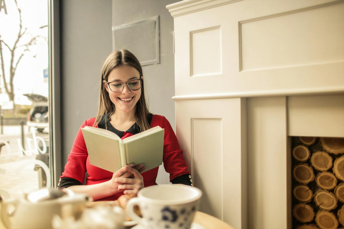 Young woman enjoying a book and a cup of coffee by the fireplace indoors.