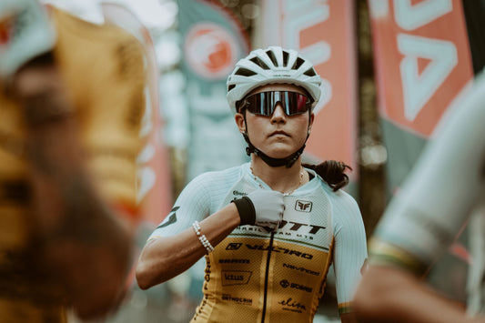 A determined cyclist adjusts her gear, preparing for a race. Captured in a vibrant outdoor setting.