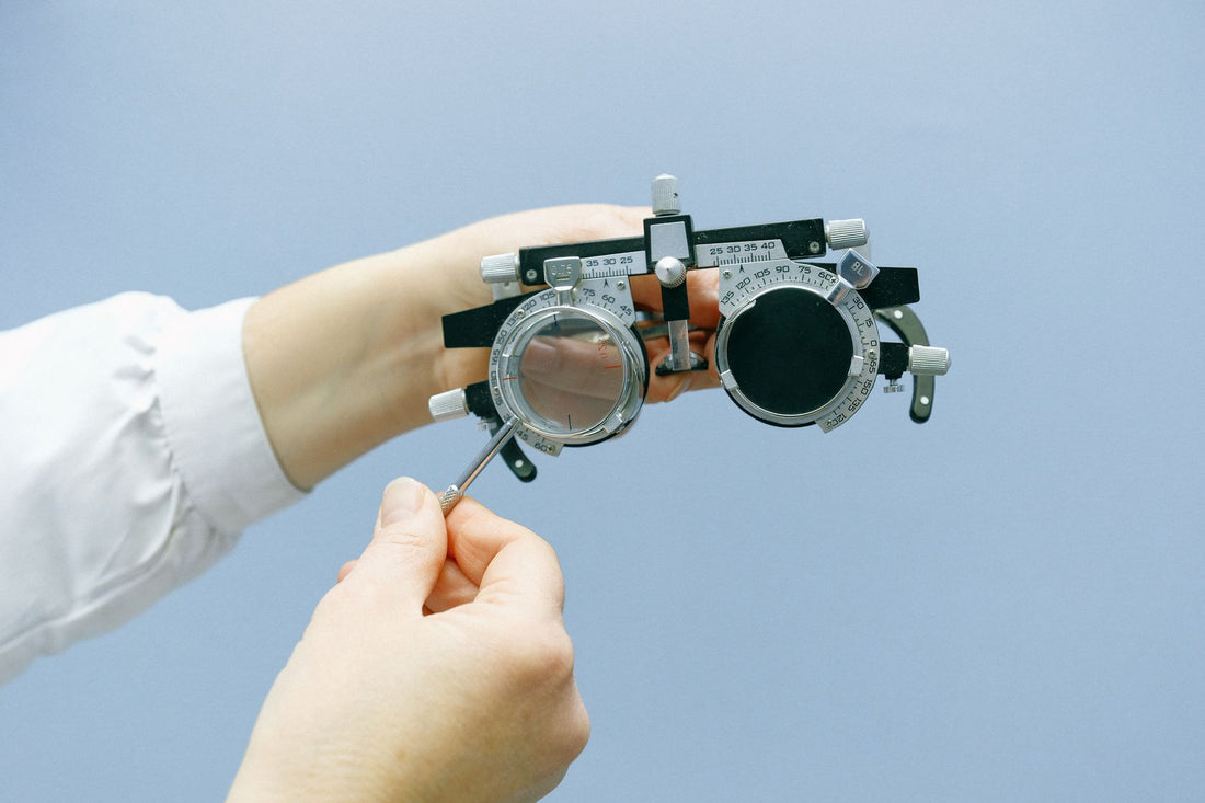 Crop anonymous ophthalmologist setting eye vision test glasses with magnifying glass and numeral scale in blue background