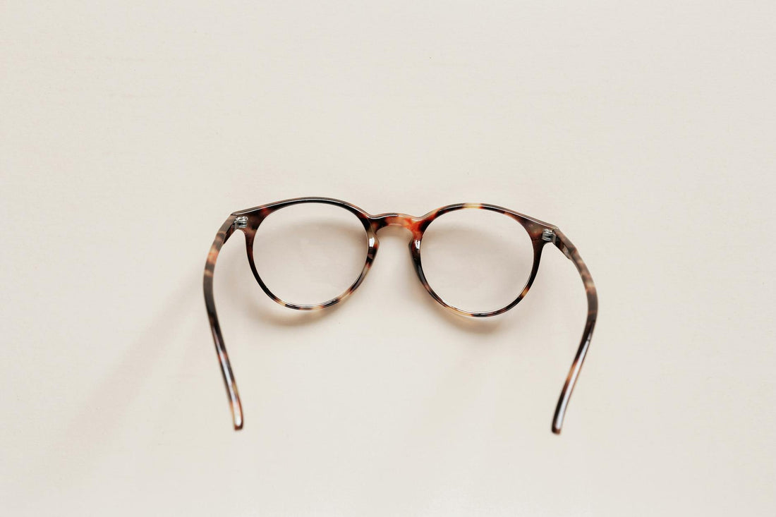 Elegant round eyeglasses with tortoise shell frame on neutral background, perfect for fashion and eyewear themes.