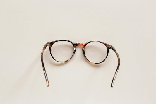 Elegant round eyeglasses with tortoise shell frame on neutral background, perfect for fashion and eyewear themes.