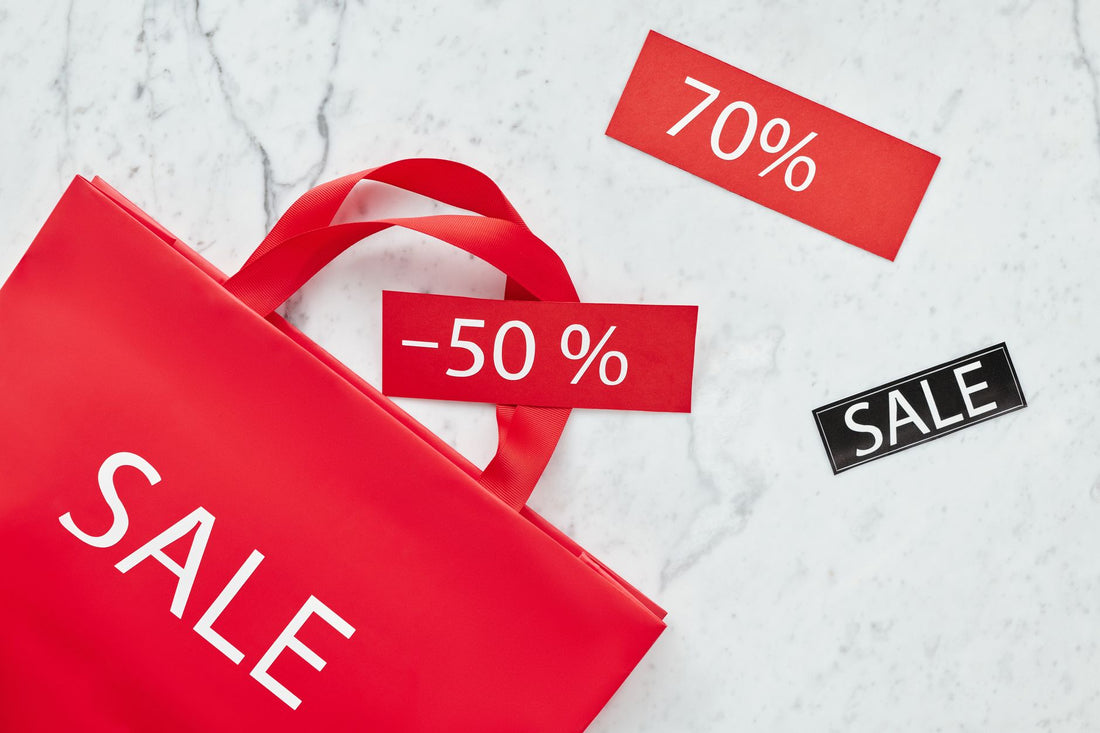 Red sale bag with 50% and 70% discount tags on marble background, perfect for retail promotions.