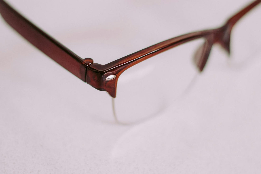 A detailed artistic close-up of a brown vintage style eyeglasses frame with a focus on the corner.