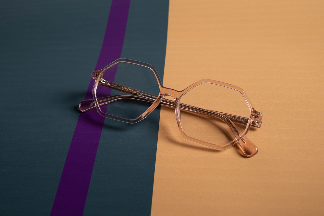 Stylish clear eyeglasses with geometric frames on a modern striped background.