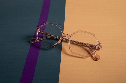 Stylish clear eyeglasses with geometric frames on a modern striped background.