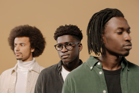 Three men posing stylishly in casual attire, looking serious. Studio shoot with a neutral background.