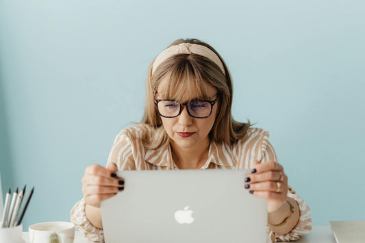 Focused woman with glasses intently using a laptop in an office setting.