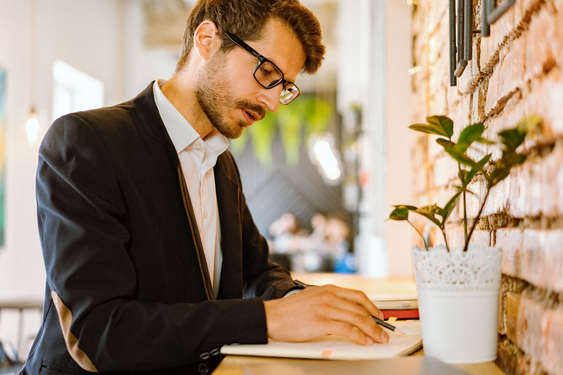 Focused businessman writing notes in a modern cafe setting with a stylish interior.
