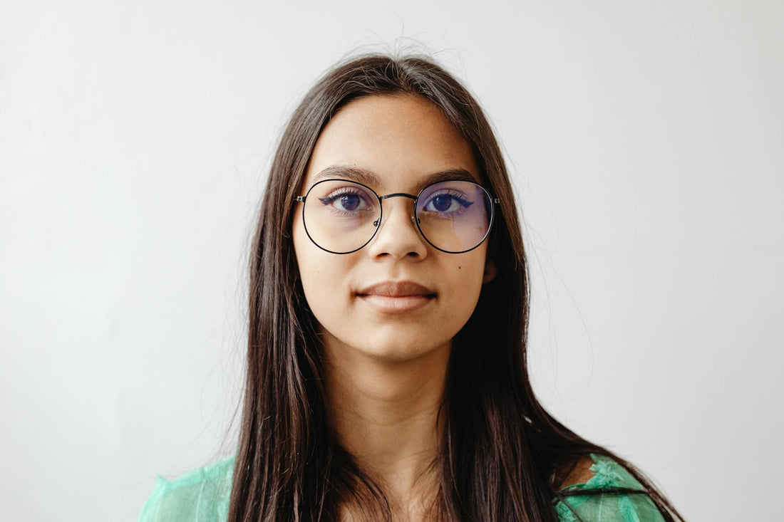 Portrait of a woman with glasses against a white background, showcasing elegance and simplicity.