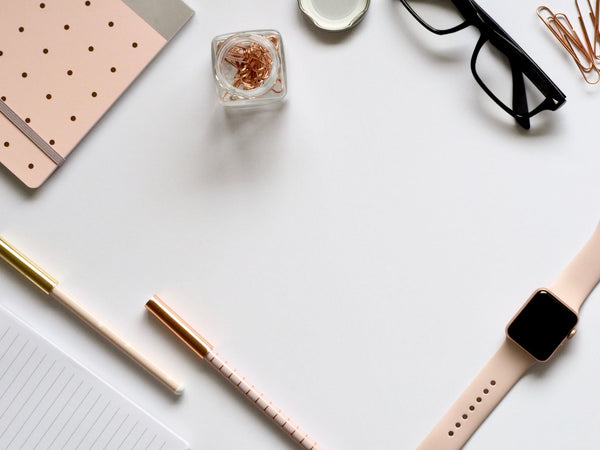 Stylish rose gold themed flatlay featuring office supplies and a smartwatch on a white background.